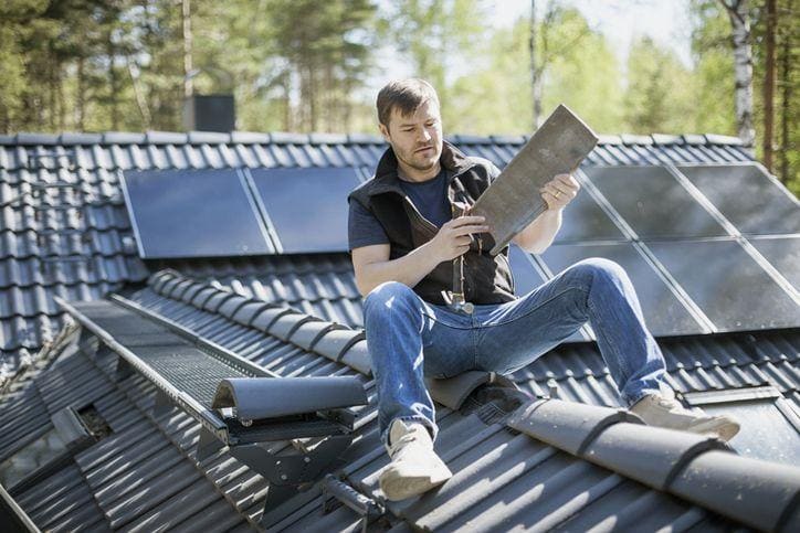 mężczyzna na dachu montujący dachówki